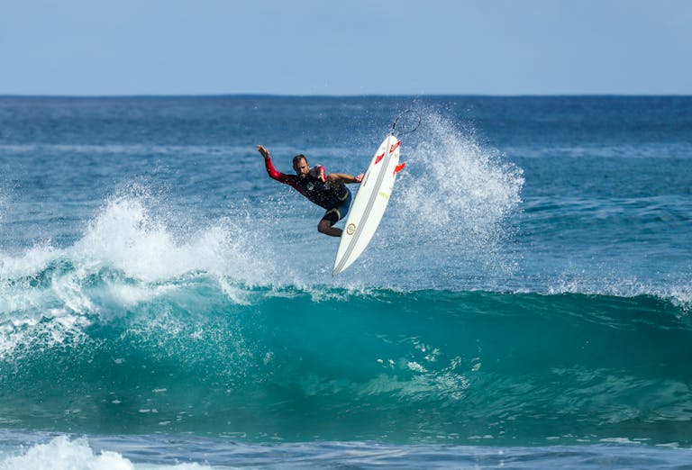 Surfer performing an aerial maneuver on a wave in Fernando de Noronha, Brazil.